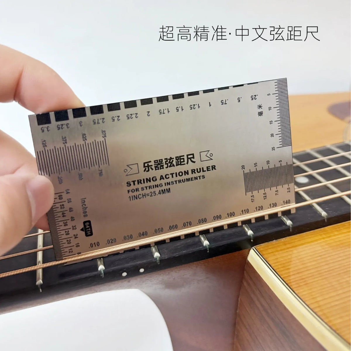Hand holding a marked string-action gauge against an acoustic guitar fretboard.