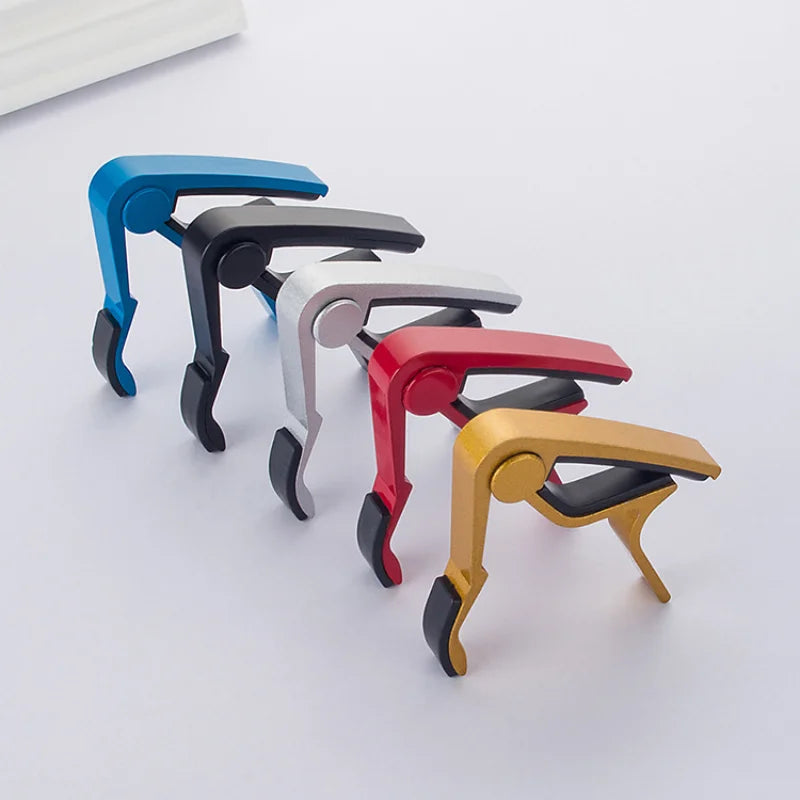 Five guitar capos in blue, black, silver, red and gold with black padded jaws.
